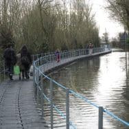 people walking across a pontoon bridge platform