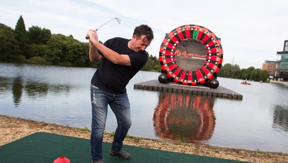 Robbie Fowler playing golf on a pontoon floating in a lake